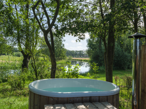 Buitenbubbelbad aan de rivier bij River Mirrorlodge, Holiday park Mölke, omgeven door groen in Nederland.