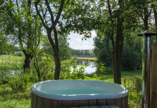 Buitenbubbelbad aan de rivier bij River Mirrorlodge, Holiday park Mölke, omgeven door groen in Nederland.