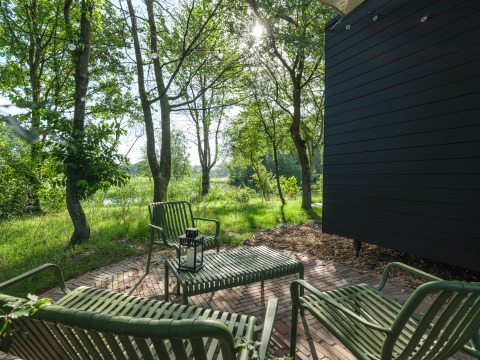 Buiten zitgedeelte bij River Mirrorlodge in Holiday park Mölke, Nederland, omringd door groen.