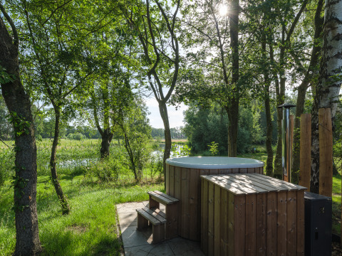 Buitenspa van hout bij River Mirrorlodge, Holiday park Mölke, Nederland, met uitzicht op bomen en vijver.