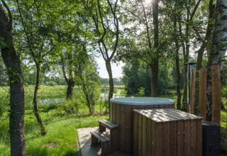 Buitenspa van hout bij River Mirrorlodge, Holiday park Mölke, Nederland, met uitzicht op bomen en vijver.