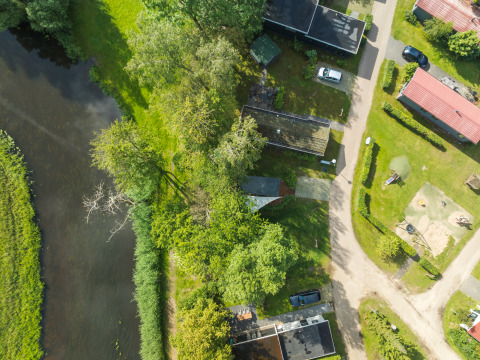 Luchtfoto van de River Mirrorlodge op vakantiepark Mölke in Nederland, naast een rivier en bomen.