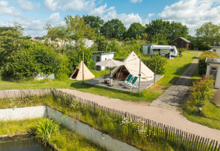 Tente teepee Blije haventent au Holiday park Mölke, Pays-Bas, entourée de verdure et d’un camping-car voisin.