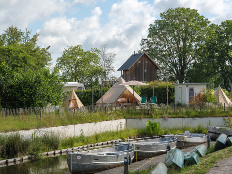 Vue sur des bateaux et tentes tipi à « Blije haventent » au parc de vacances Mölke, Pays-Bas, entouré de verdure.