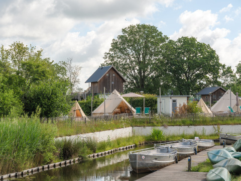 Tentes tipi au Holiday park Mölke aux Pays-Bas, avec barques sur un canal et végétation verdoyante autour.
