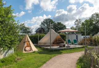 Moderne tipi-telte og afslapningsområde på Holiday park Mölke i Holland under en blå himmel.