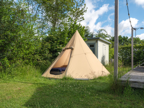 De Blije haventent tipi-tent bij vakantiepark Mölke in Nederland, omringd door gras en bomen.