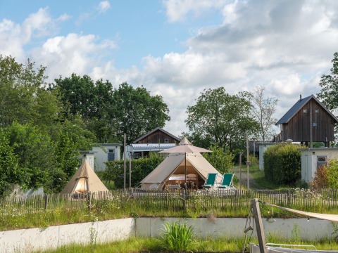 Tente tipi 'Blije haventent' au parc de vacances Mölke aux Pays-Bas, entourée de verdure et de chalets.