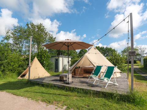 Udendørs teepee-telt med terrasse, parasol og liggestole på Holiday park Mölke i Nederlandene.