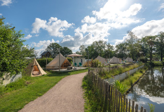 Tipis installés près de l'eau au parc de vacances Mölke aux Pays-Bas, dans un cadre verdoyant.