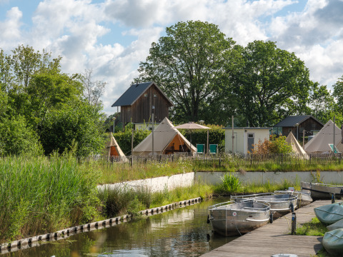 Tente tipi « Blije haventent » au Holiday park Mölke aux Pays-Bas, avec barques et verdure luxuriante.