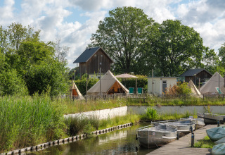 Tente tipi « Blije haventent » au Holiday park Mölke aux Pays-Bas, avec barques et verdure luxuriante.