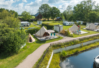 Luchtfoto van tipi-tenten en caravans bij het water in vakantiepark Mölke in Nederland.