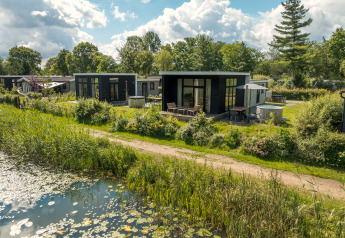 Photo d'un lodge River Cabin avec jacuzzi, situé près d'un étang et entouré de verdure naturelle luxuriante.