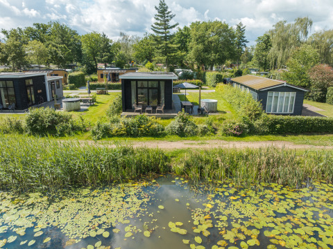 Moderne River Cabin ved Holiday park Mölke i Holland, omgivet af grønt og udsigt til en dam.