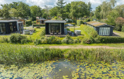 Stijlvolle River Cabin in vakantiepark Mölke, Nederland, met vijverzicht en groene omgeving.