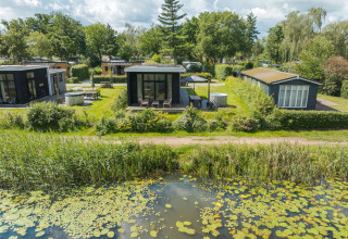 Moderne River Cabin ved Holiday park Mölke i Holland, omgivet af grønt og udsigt til en dam.