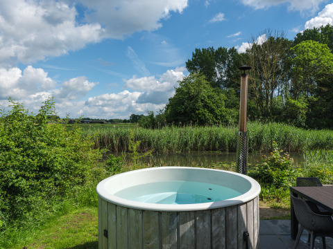 Buitenbad bij River Cabin in vakantiepark Mölke in Nederland, met uitzicht op natuur en blauwe lucht.