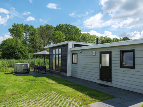 Buitenkant van de River Cabin bij Holiday park Mölke in Nederland, met terras, parasol en natuur.