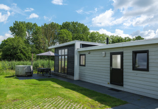 Buitenkant van de River Cabin bij Holiday park Mölke in Nederland, met terras, parasol en natuur.
