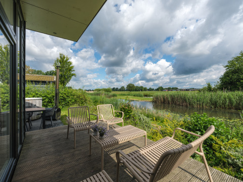 Udsigt fra River Cabin på Holiday park Mölke i Holland, med terrasse og naturskønt landskab ved vandet.