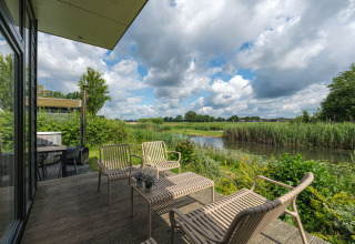 Udsigt fra River Cabin på Holiday park Mölke i Holland, med terrasse og naturskønt landskab ved vandet.
