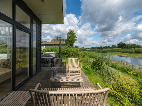 Udendørs terrasse ved River Cabin på Holiday park Mölke, Holland, med udsigt over flod og marker.