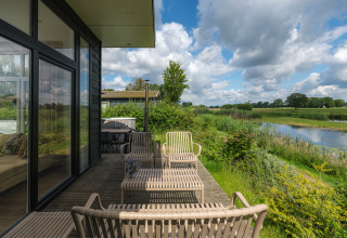 Udendørs terrasse ved River Cabin på Holiday park Mölke, Holland, med udsigt over flod og marker.
