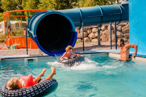 Bambini si divertono con uno scivolo d’acqua al Camping La Sténiole, Grand Est, Francia, con un adulto presente.