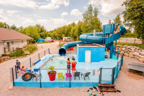 Enfants s'amusant dans la piscine avec toboggan au Camping La Sténiole, parc de vacances à Grand Est, France.