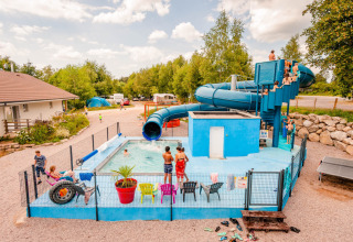 Niños disfrutando de una piscina con tobogán en Camping La Sténiole, parque vacacional en Grand Est, Francia.