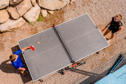 Deux personnes jouent au tennis de table en plein air au Camping La Sténiole, dans le Grand Est, France.