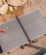 Two people play outdoor table tennis at Camping La Sténiole, a holiday park in Grand Est, France.