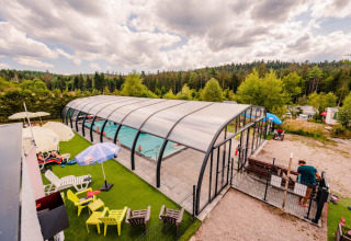 Piscine couverte entourée de chaises longues et de nature au Camping La Sténiole en Grand Est, France.