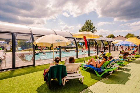 Vakantiegangers relaxen aan het overdekte zwembad van Camping La Sténiole in Grand Est, Frankrijk.