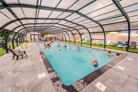 Overdekt zwembad met mensen die zwemmen en spelen op Camping La Sténiole in Grand Est, Frankrijk.