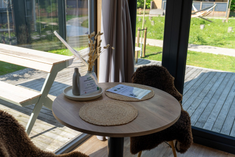 Coin repas chaleureux dans Tiny Home à Urban-Gardens Gent, Belgique, avec vue sur terrasse et jardin.