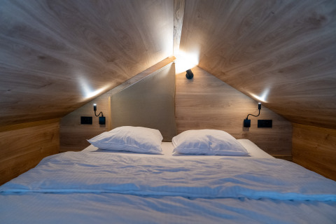 Chambre mezzanine et lit double sous plafond en bois inclinée dans Tiny Home à Urban-Gardens Gent, Belgique.