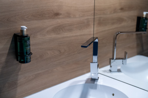 Lavabo moderno con grifo cuadrado y dispensador de jabón en pared en Tiny Home de Urban-Gardens Gent, Bélgica.