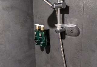 Douche dans une tiny house à Urban-Gardens Gent, Belgique, dotée de robinets modernes et murs foncés.
