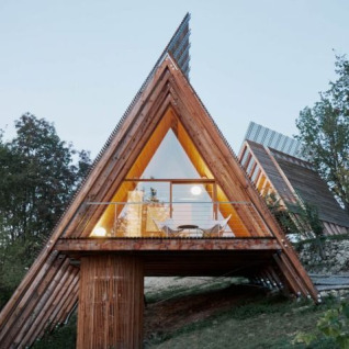 A-frame glamping accommodation named 'Little leisure lodge – Lodges Piemonte' nestled in a wooded hillside.