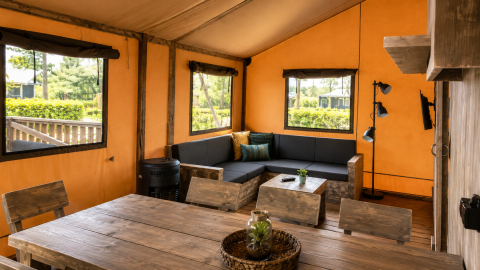 Intérieur d'une tente safari de luxe au Camping 't Veld aux Pays-Bas, avec mobilier en bois rustique.