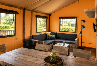 Intérieur d'une tente safari de luxe au Camping 't Veld aux Pays-Bas, avec mobilier en bois rustique.