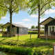 Deux chalets de plage avec terrasse en bois sur pelouse verte à la lodge Beach chalet par une journée ensoleillée.