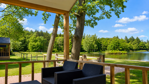 Vue depuis une terrasse de chalet de plage au Camping 't Veld aux Pays-Bas, donnant sur un lac et des arbres verts.
