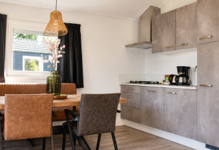 Cucina moderna e zona pranzo in uno chalet Beach al Camping 't Veld, Paesi Bassi, con tavolo in legno e mobili grigi.