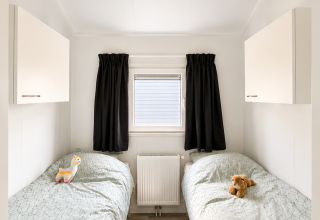 Dormitorio luminoso en Beach chalet de Camping 't Veld, Países Bajos, con dos camas individuales y peluches.