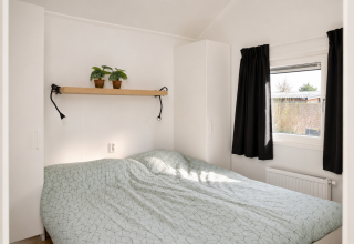 Chambre lumineuse dans le Beach chalet au Camping 't Veld aux Pays-Bas, avec plantes et lumière du jour.