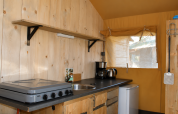 Zona de cocina en la tienda safari Comfort de Camping 't Veld en Países Bajos, con hornillo y fregadero.