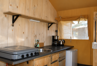 Zona de cocina en la tienda safari Comfort de Camping 't Veld en Países Bajos, con hornillo y fregadero.